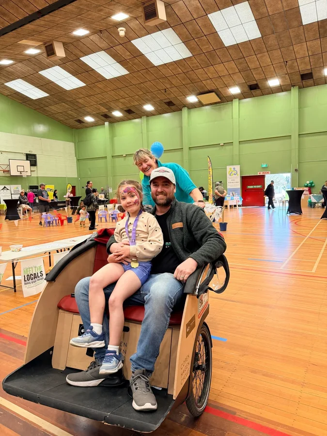 Adult and child seated in a rickshaw inside an event hall