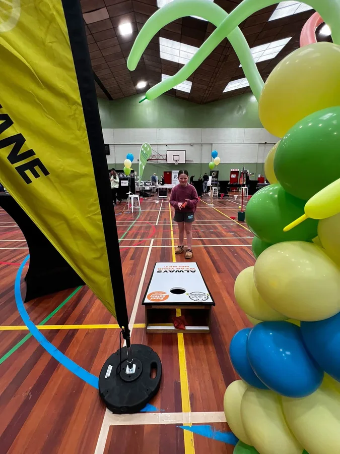 Cornhole activity beside balloons and event displays